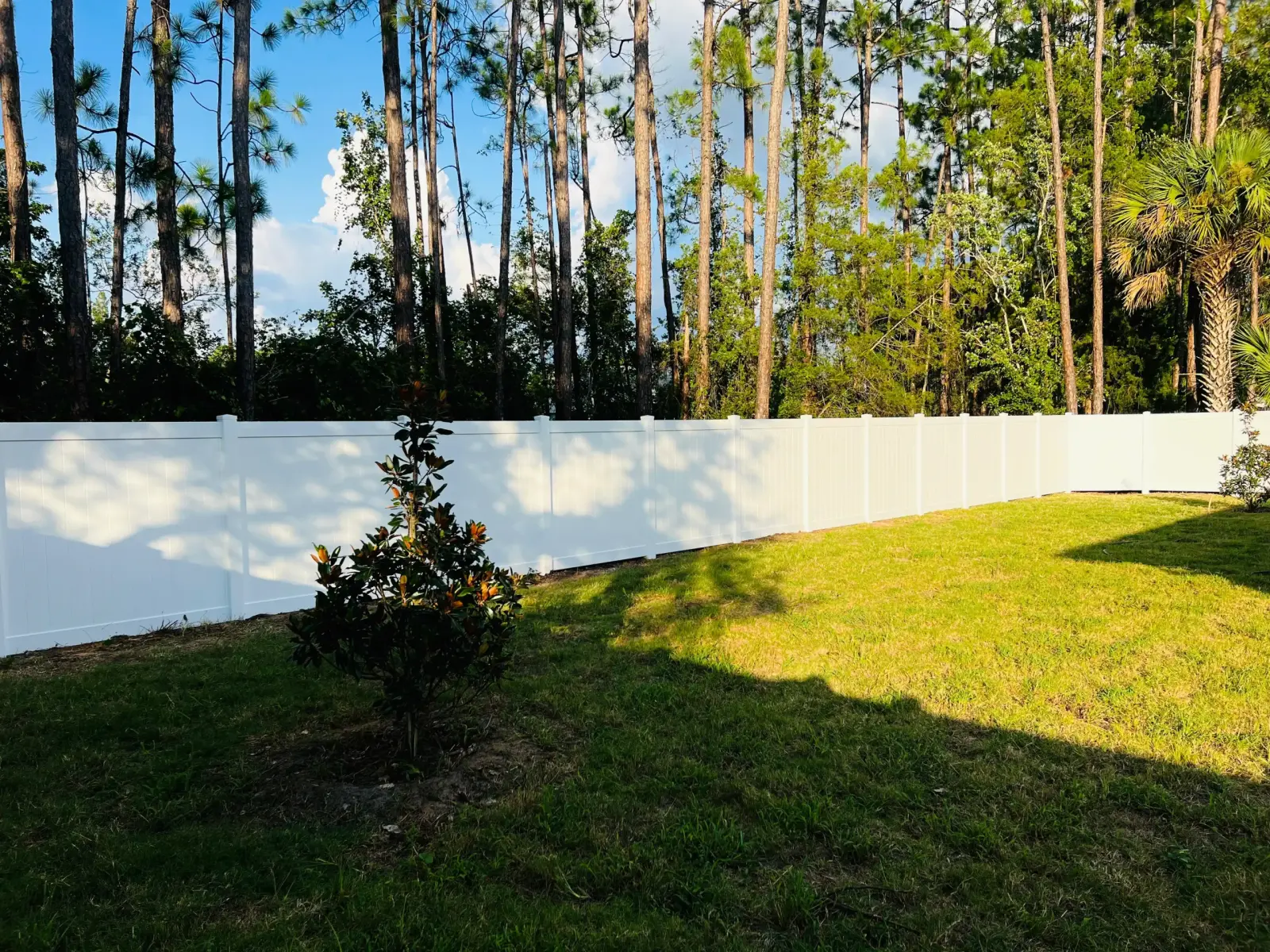 White vinyl privacy fence along a residential street next to a coastal-style home